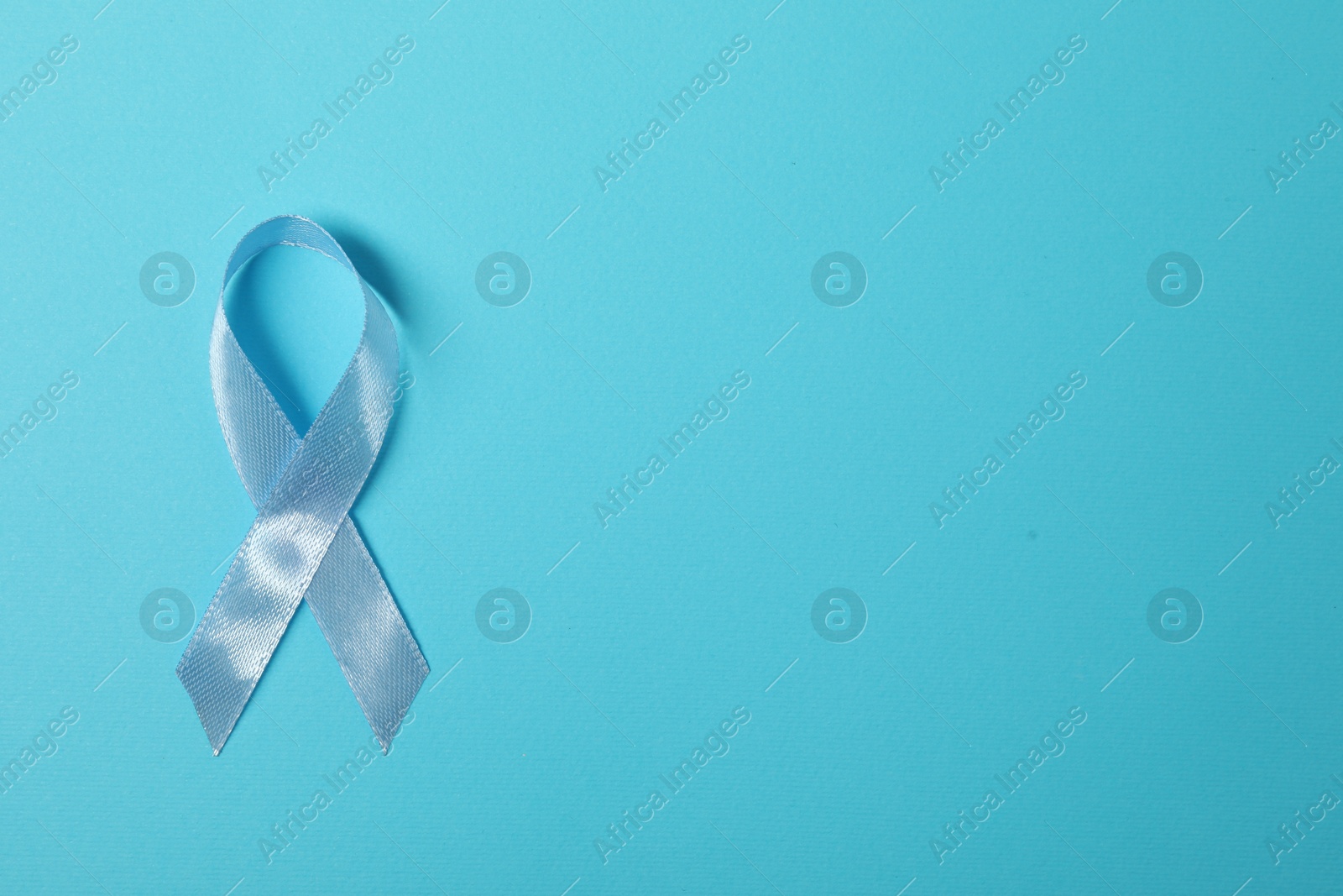 Photo of Light blue ribbon on color background, top view with space for text. Prostate cancer awareness