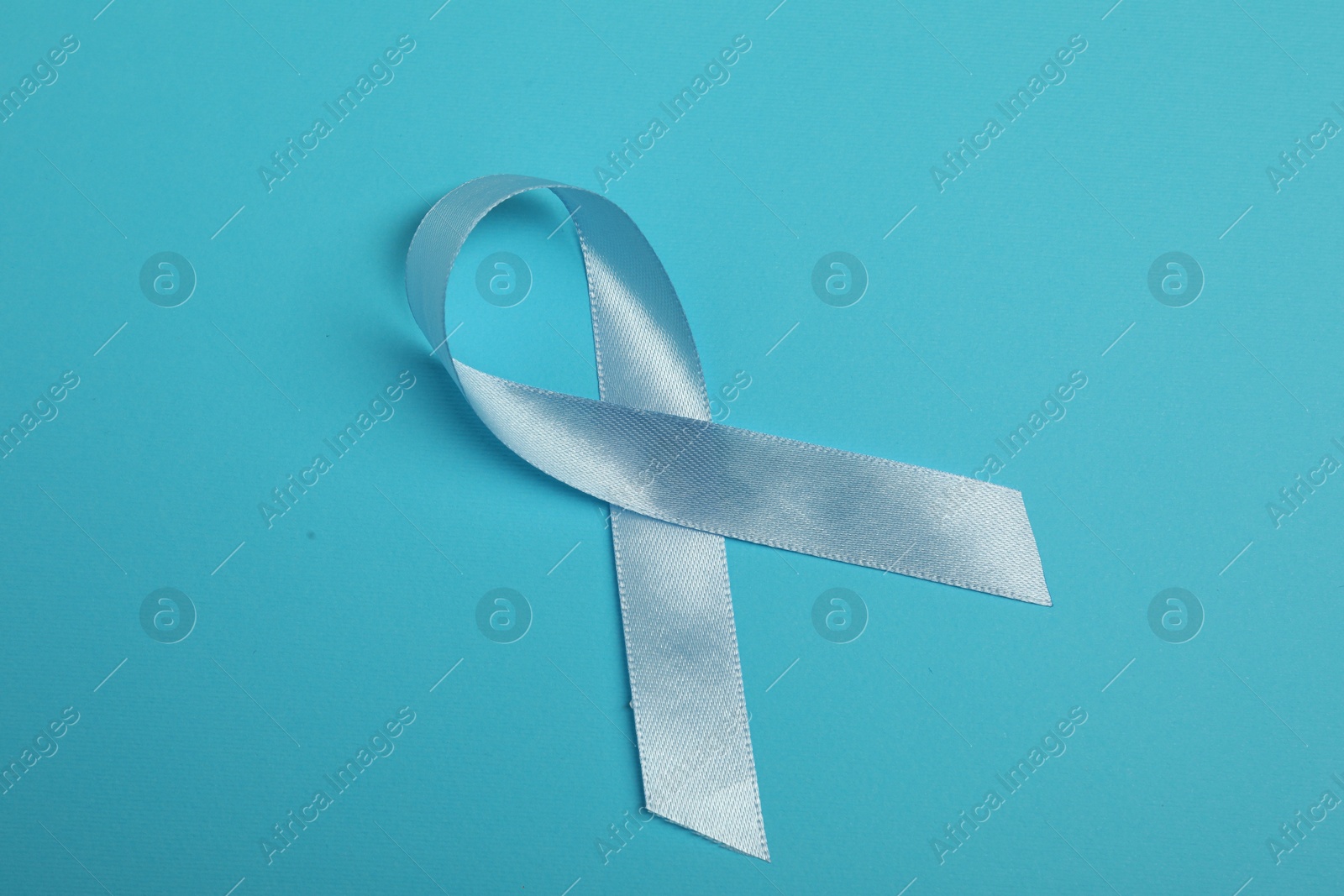 Photo of Light blue ribbon on color background, top view. Prostate cancer awareness