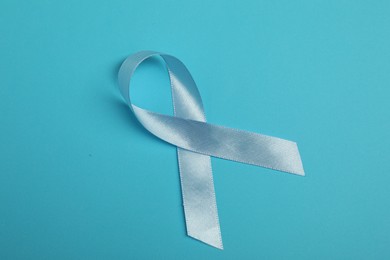 Photo of Light blue ribbon on color background, top view. Prostate cancer awareness