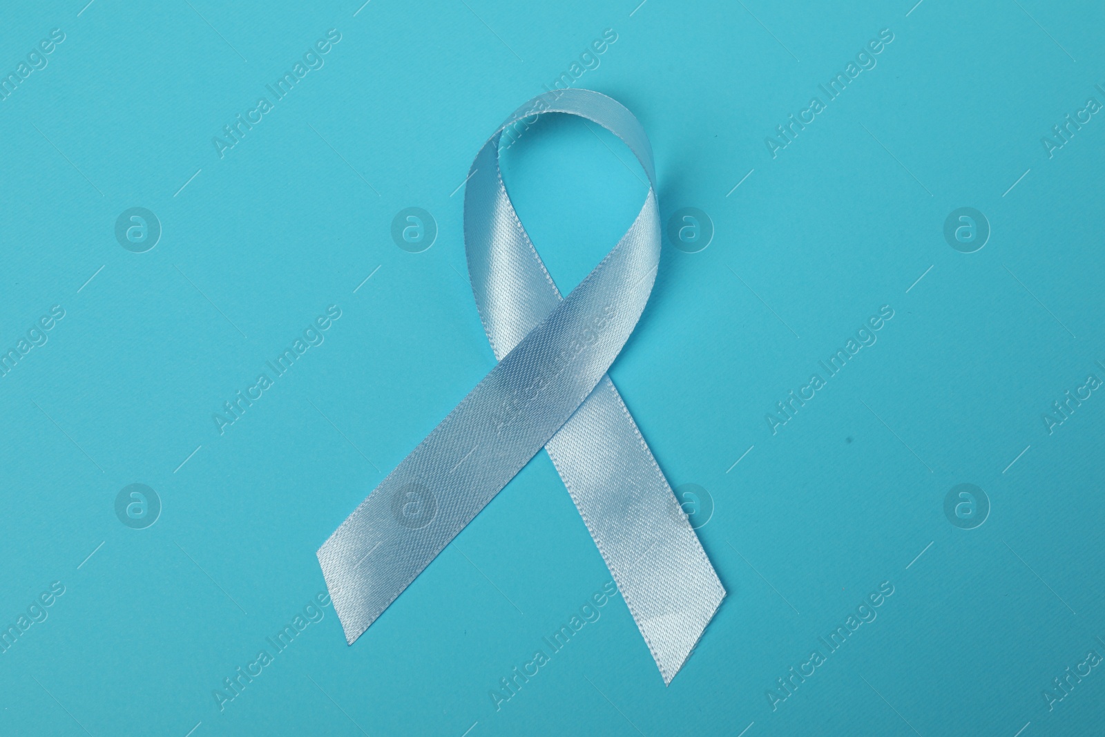 Photo of Light blue ribbon on color background, top view. Prostate cancer awareness