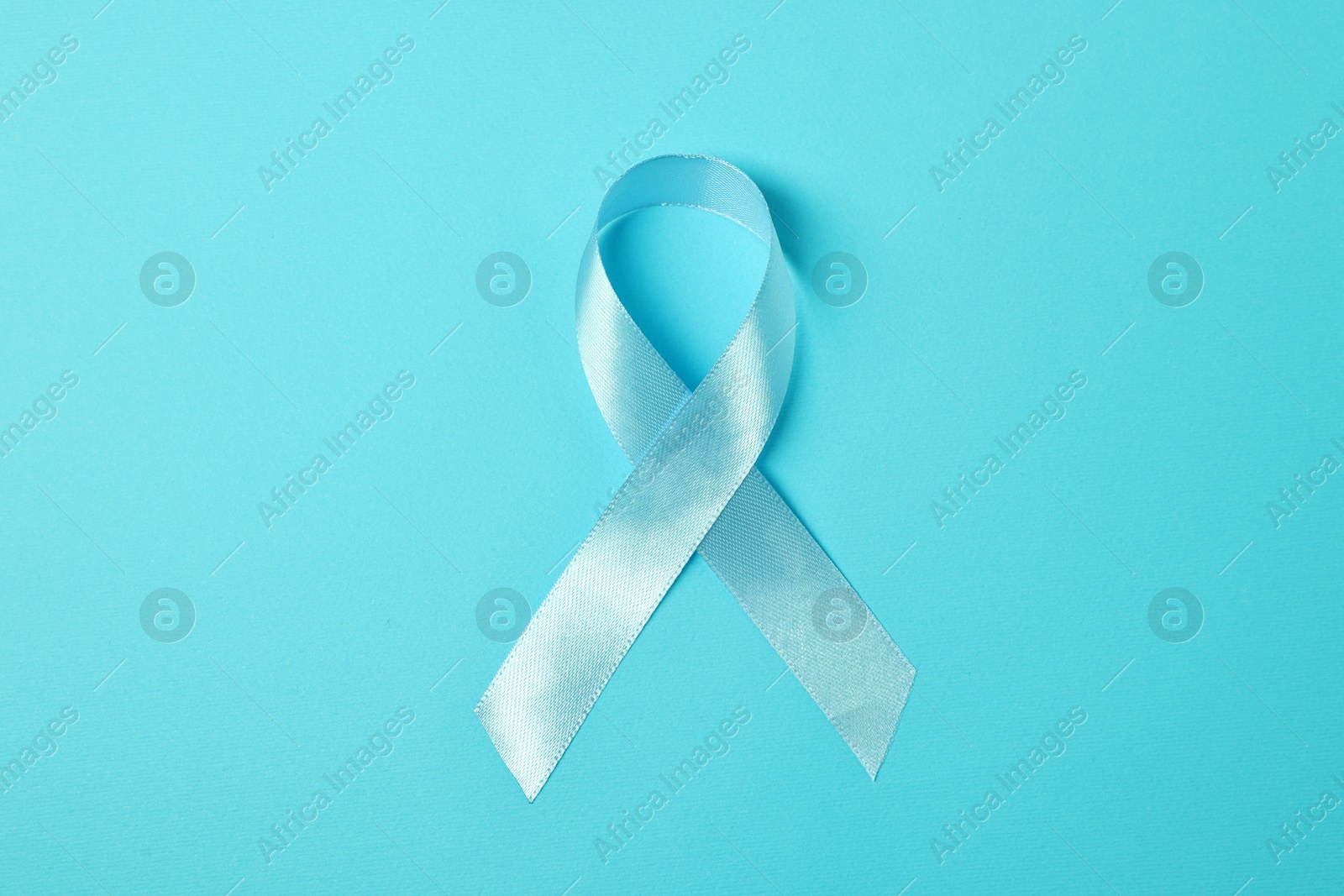 Photo of Light blue ribbon on color background, top view. Prostate cancer awareness