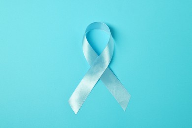 Photo of Light blue ribbon on color background, top view. Prostate cancer awareness