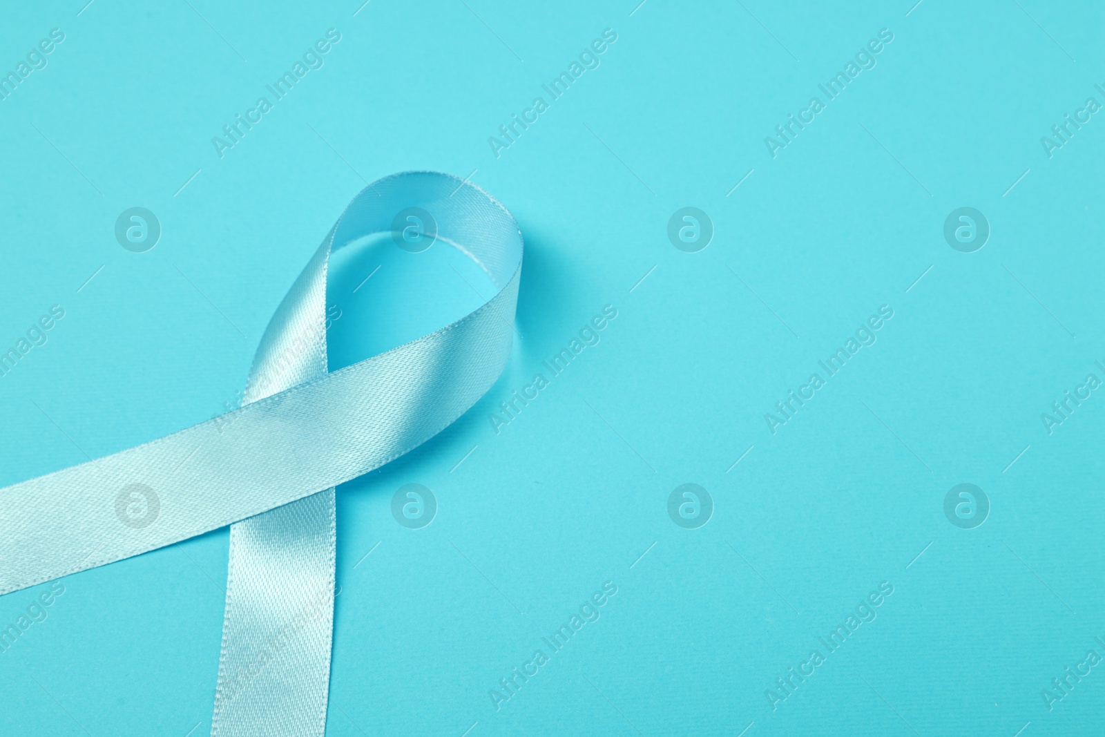 Photo of Prostate cancer awareness. Light blue ribbon on color background, closeup. Space for text