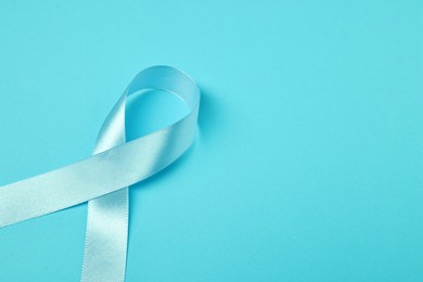 Photo of Prostate cancer awareness. Light blue ribbon on color background, closeup. Space for text