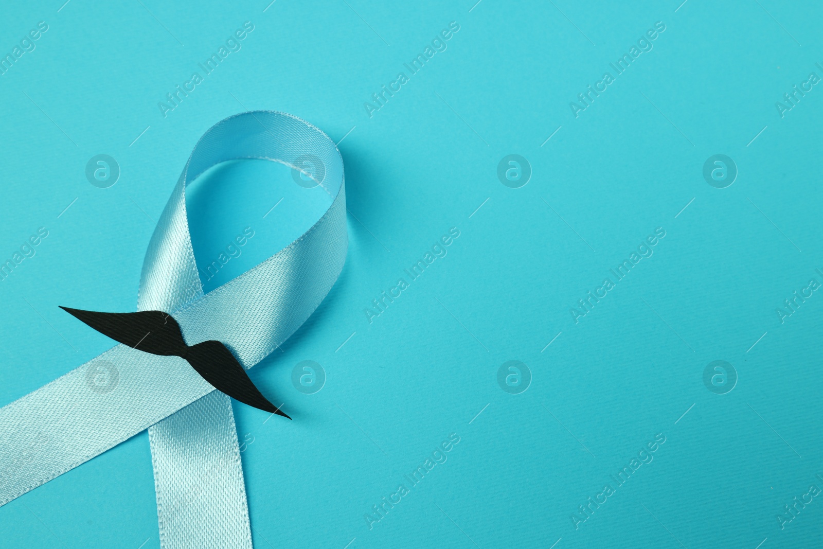 Photo of Prostate cancer awareness. Light blue ribbon and fake mustache on color background, closeup. Space for text