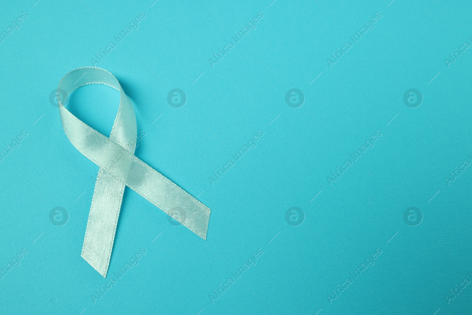 Photo of Light blue ribbon on color background, top view with space for text. Prostate cancer awareness