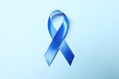 Photo of Blue ribbon on light background, top view. Prostate cancer awareness