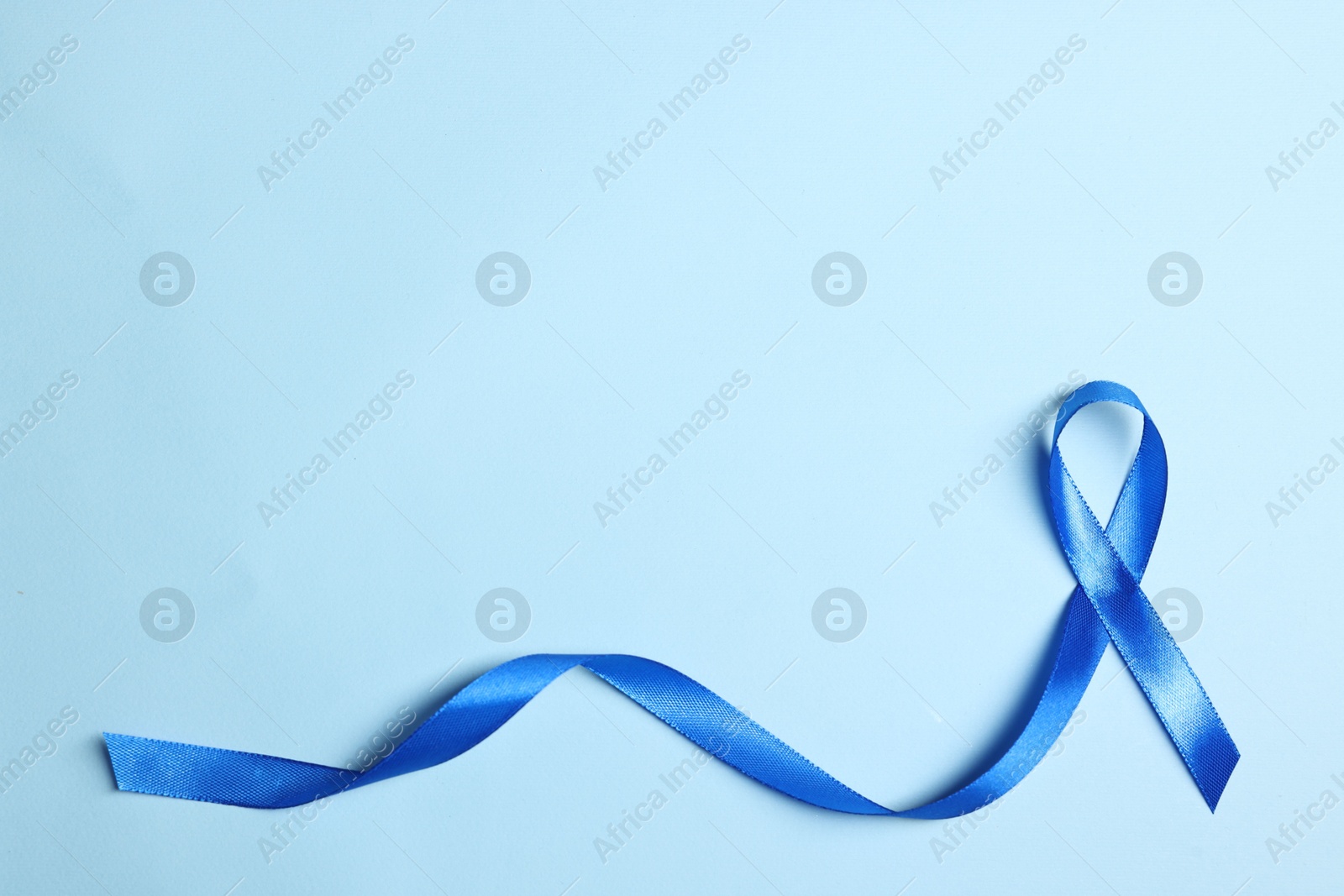 Photo of Blue ribbon on light background, top view with space for text. Prostate cancer awareness