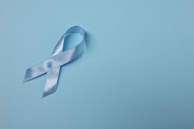 Photo of Light blue ribbon on color background, top view with space for text. Prostate cancer awareness