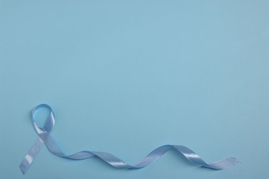 Photo of Light blue ribbon on color background, top view with space for text. Prostate cancer awareness