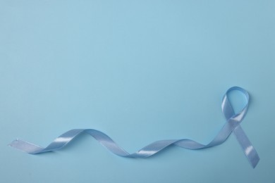 Photo of Light blue ribbon on color background, top view with space for text. Prostate cancer awareness