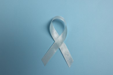 Photo of Light blue ribbon on color background, top view. Prostate cancer awareness