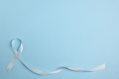 Photo of Light blue ribbon on color background, top view with space for text. Prostate cancer awareness