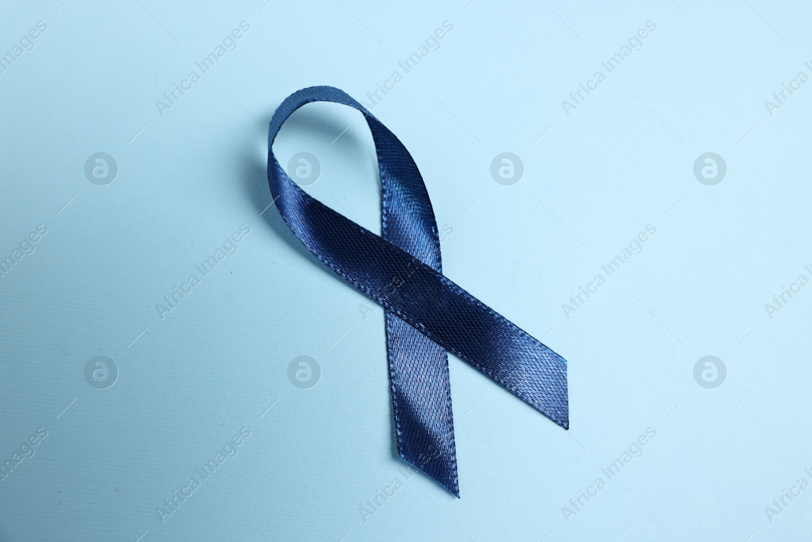 Photo of Dark blue ribbon on color background, top view. Prostate cancer awareness