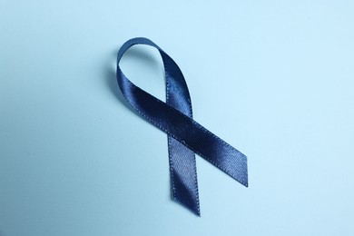 Dark blue ribbon on color background, top view. Prostate cancer awareness