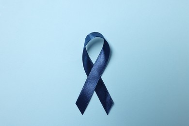 Photo of Dark blue ribbon on color background, top view. Prostate cancer awareness