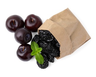Photo of Paper bag with delicious prunes, fresh ripe plums and mint isolated on white, top view