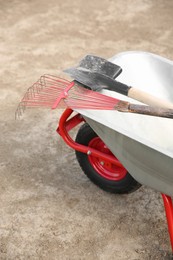 Photo of Wheelbarrow with rake and shovel outdoors. Gardening tools