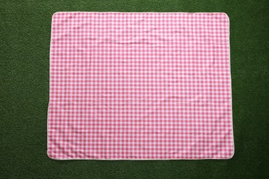 Photo of Checkered picnic tablecloth on green grass, top view