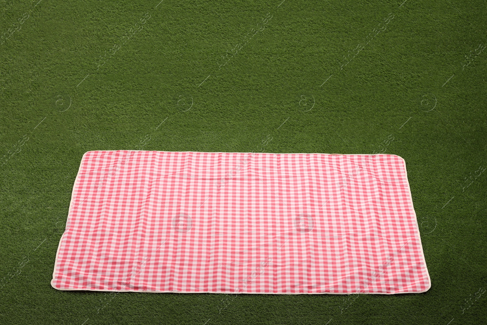Red checkered picnic tablecloth on green grass Photo of Red checkered picnic tablecloth on green grass