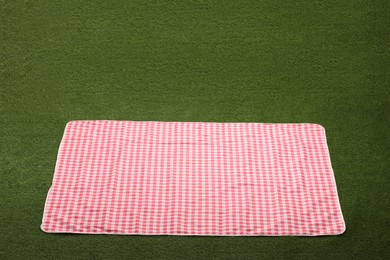 Photo of Red checkered picnic tablecloth on green grass