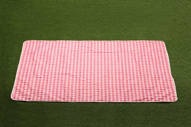 Photo of Red checkered picnic tablecloth on green grass