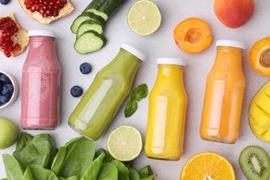 Glass bottles of tasty smoothies and different products on white table, flat lay