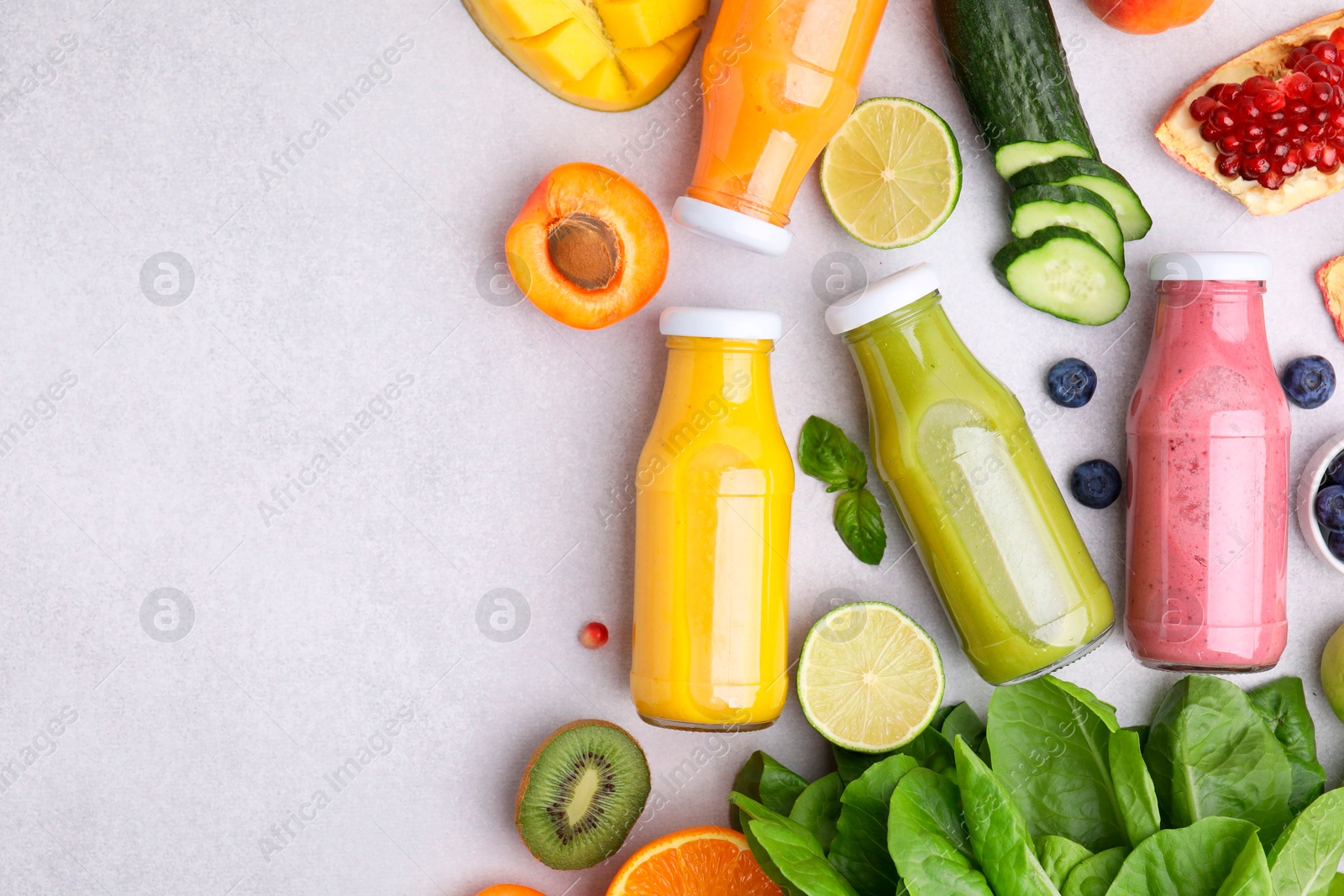 Photo of Glass bottles of tasty smoothies and different products on white table, flat lay. Space for text