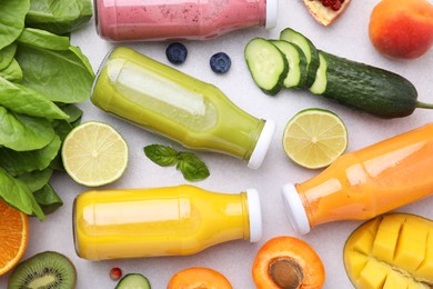 Glass bottles of tasty smoothies and different products on white table, flat lay