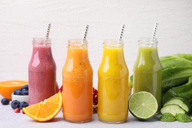 Photo of Glass bottles of tasty smoothies and different products on white table