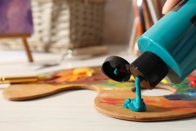 Woman mixing paints on palette at wooden table indoors, closeup