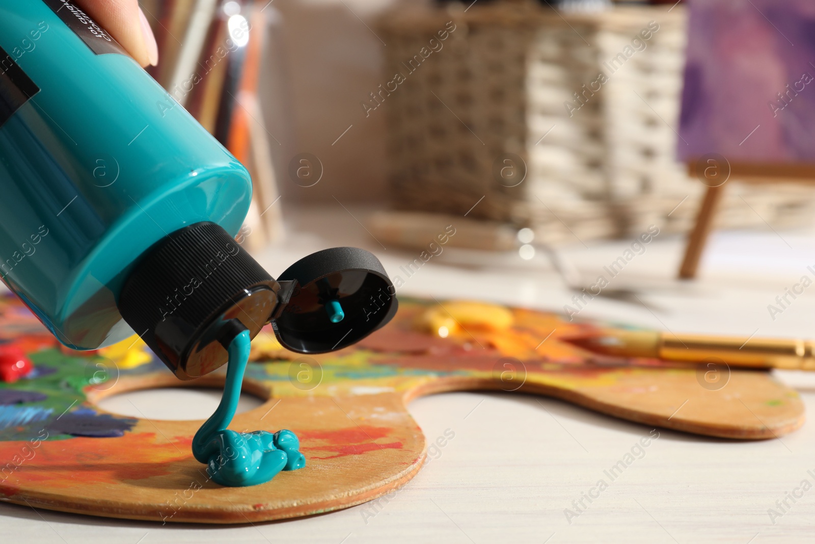 Photo of Woman mixing paints on palette at wooden table indoors, closeup