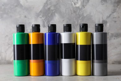 Photo of Acrylic paints of different colors on grey table