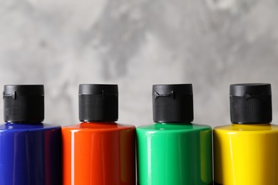 Photo of Acrylic paints of different colors against blurred background, closeup