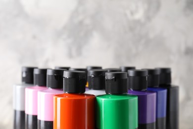 Photo of Acrylic paints of different colors against blurred background, closeup