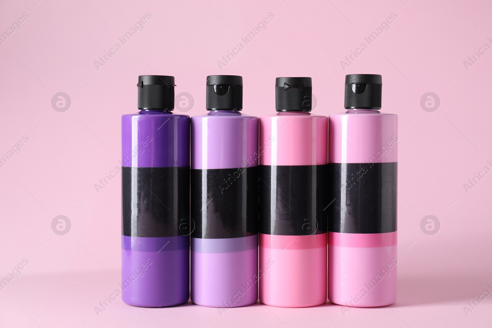 Photo of Acrylic paints of different colors on pink background