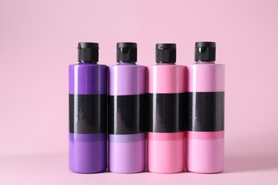 Photo of Acrylic paints of different colors on pink background