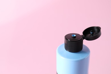 Photo of Light blue acrylic paint in bottle on pink background, closeup. Space for text