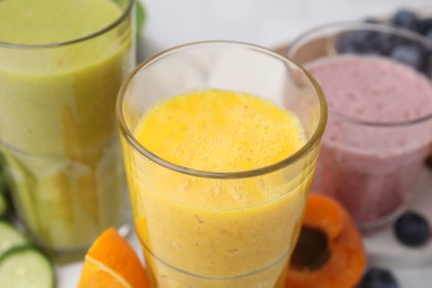 Photo of Tasty smoothies in glasses and ingredients on white table, closeup