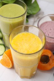 Photo of Tasty smoothies in glasses and ingredients on white table, closeup