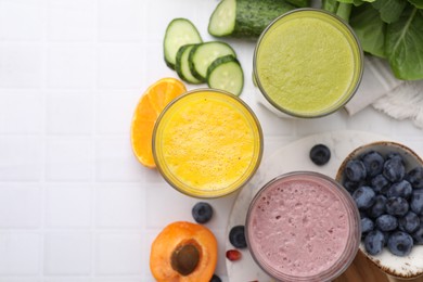 Tasty smoothies in glasses and ingredients on white tiled table, flat lay. Space for text