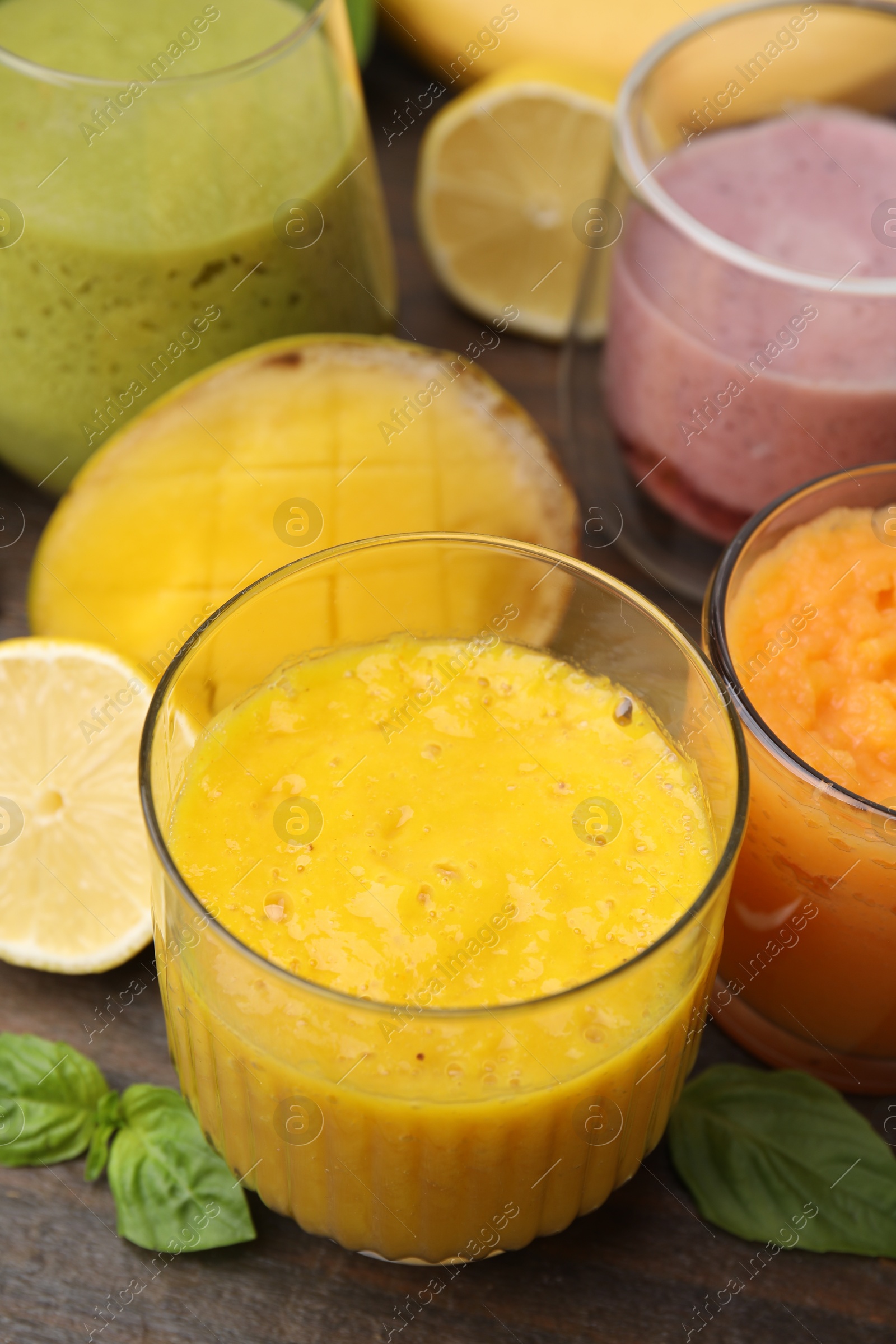 Photo of Tasty smoothies in glasses and ingredients on wooden table, closeup