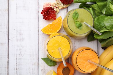 Photo of Tasty smoothies in glasses and ingredients on wooden table, flat lay. Space for text