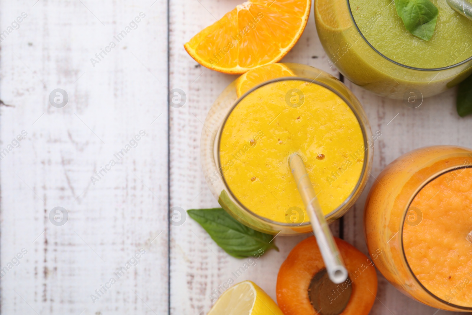 Photo of Tasty smoothies in glasses and ingredients on wooden rustic table, flat lay. Space for text