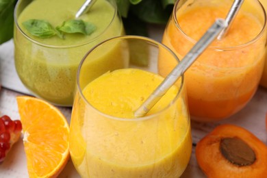 Photo of Tasty smoothies in glasses and ingredients on table, closeup