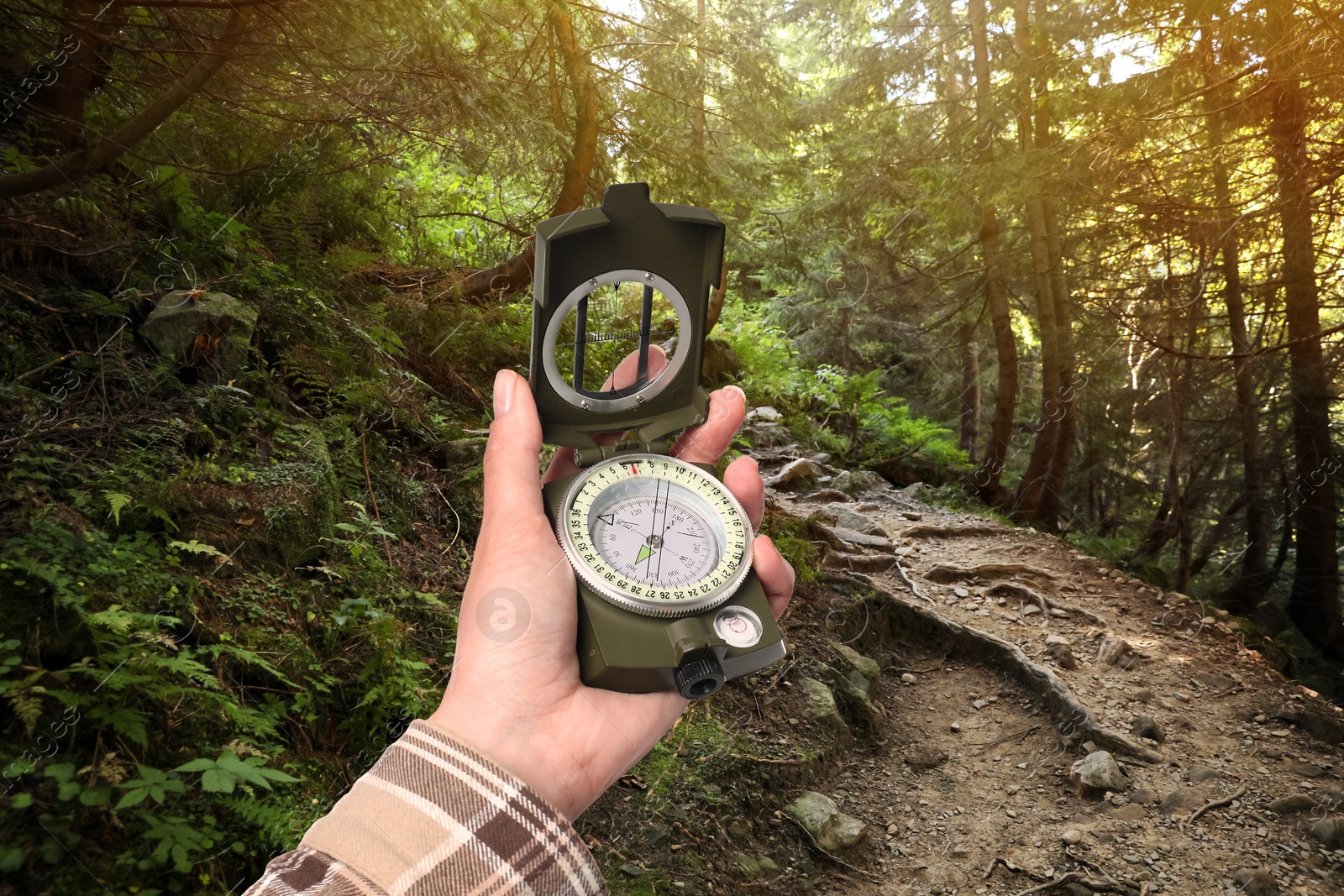 Image of Woman holding compass in mountain forest, closeup