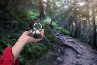 Image of Woman holding compass in mountain forest, closeup