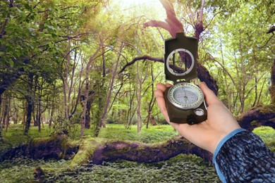 Image of Woman holding compass in sunlit forest, closeup