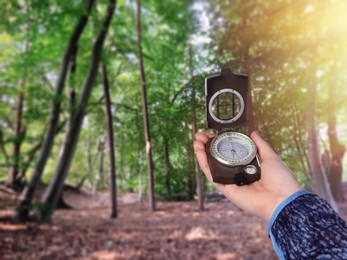 Image of Woman holding compass in beautiful forest, closeup