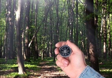 Image of Man holding compass in lush forest on sunny day, closeup